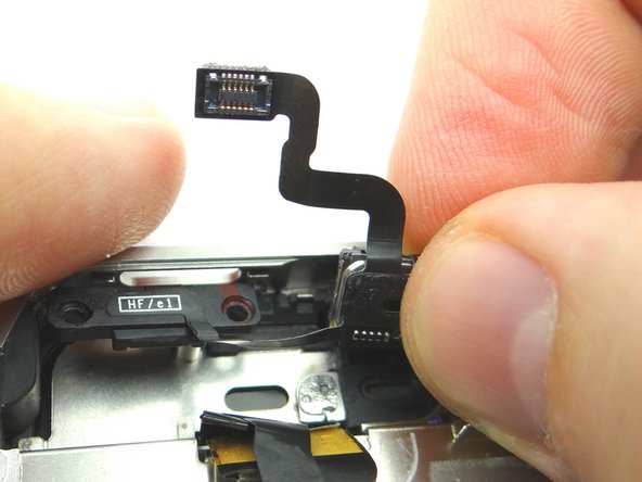 Picture 2: Use your thumb and index finger to pinch the speaker.  Gently separate the speaker from the adhesive holding it in place.