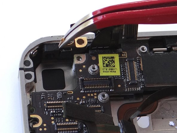 Remove Gold Grounding Clip with curved tip tweezers.  Lift straight up and be careful not to scratch the logic board with the tweezers.