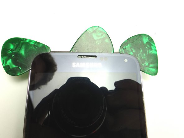 Run the guitar pick along the top and rest it over the earpiece speaker.