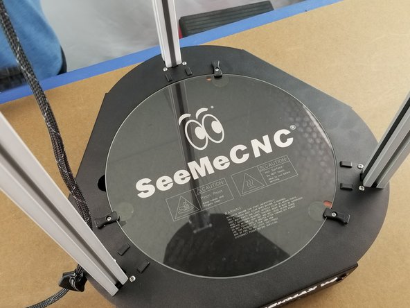 Holding the glass by the edges, place the glass into the recess for the heated bed.