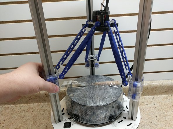 Gently list up on each of the three carriages a little at a time until they are all above the spool of filament attached to the build plate.