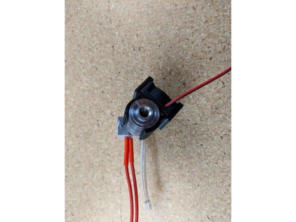 Rotate the fan shroud  so it is positioned in pic 2.  The fan should be approximately at the corner of the heater block opposite of the thermistor wires.