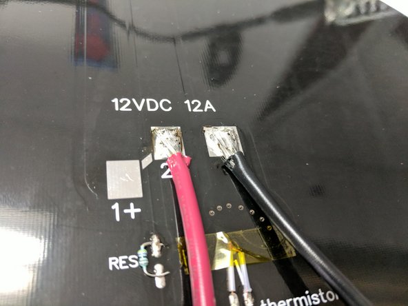 Fan out the exposed strands of wire for the 12awg red and black wires. Solder them to the heated bed in the location indicated ( The - pad and the 2+ pad) NOTE: These are large wires and pads. Ensure that the pads and wire strands get hot enough to wick the solder throughout resulting a good solder joint. Apply additional solder as needed.