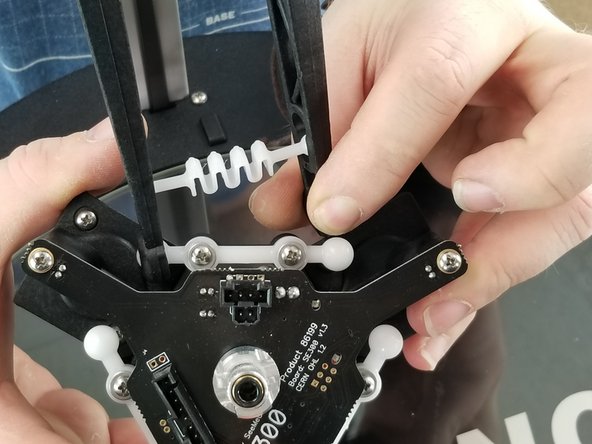 Snap one arm onto the ball joint of the hotend and stretch the spring to fit around the other ball joint as shown in Pics 1 and 2.