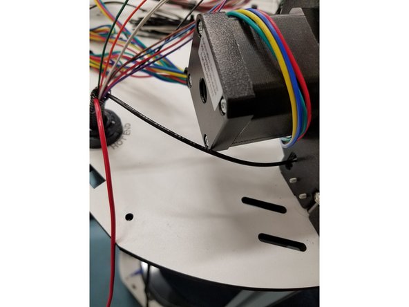 Thread  the Black 20awg negative power wire from the Hot End Whip through the injection molded motor mount on the X tower. Cut it to length and strip back the wire about 2mm.