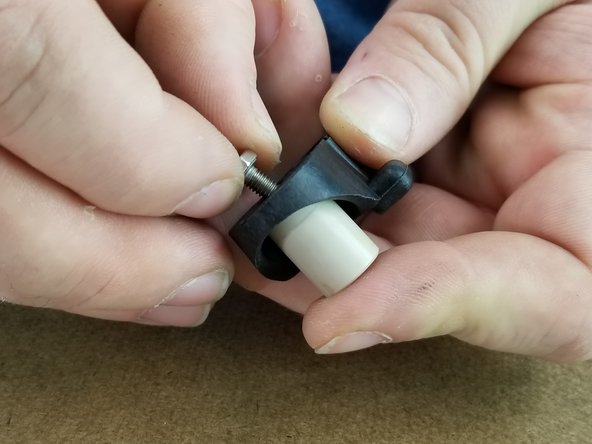 Using the hex head bolt, attach the PEEK Isolator (the tan piece) to the black cup holder piece.