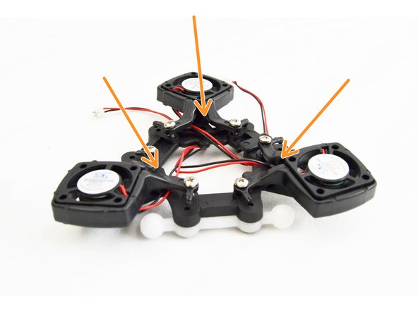 Loosely route the fan wires for each fan up and in between the legs of the layer fan shroud mount. This is indicated with orange arrows.