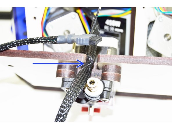 Measure 550mm from the end of the whip with the 8 pin pluggable connector. This is the point that we want to position the whip to secure it to the cover with the extruder motor. The 550mm point should be even with the outside face of the cover (indicated with a blue arrow).