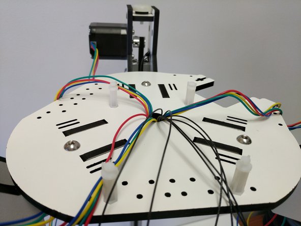 Route the wires through the hole in the center of the base assembly bottom plate. The machine is still upside down at this point and the wires should be coming up through that hole.