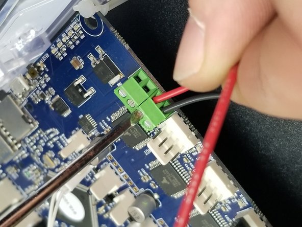 With the terminals open, insert the black wire into the position closest to the white connector and tighten to secure it.