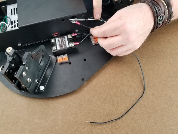 Take the 400mm black wire with a ring terminal on one end and bare wire on the other side and feed it into the power supply bracket hole as shown.