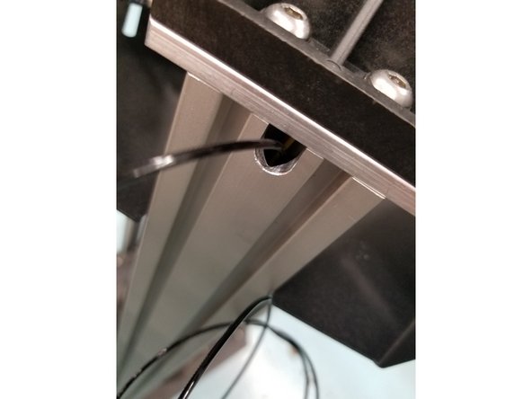 Snap off a long piece of filament and fish it down the tower, from the notch facing the outside of the machine to the hold the extruder is hanging from.