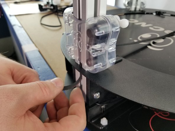 Insert the belt up the extrusion from the outside, making sure to go behind the sheet metal frame.