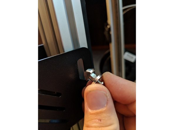 On the right side of the extruder, insert the other hanger through the extruder mount and into the Y-Tower extusion. Rotate it clockwise and tighten the screw to lock it in place as shown in Figure 2.