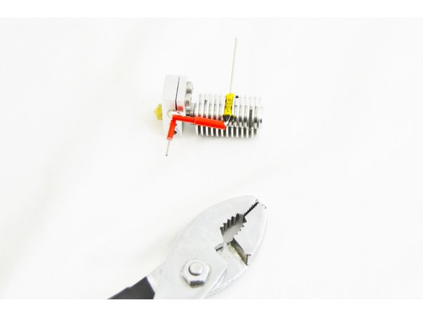 Use a pair of pliers to crimp the ferrule to the leads. Do this in three steps: roughly locate the midpoint of the ferrule and crimp the upper portion (side with the thermal safety fuse lead), then the lower side (side with the heater cartridge lead), and finally crimp, one last time in the center of the ferrule.