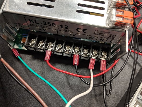 The ground (green) and neutral (white) wires go to their respective locations on the power supply. Unscrew the clamps and reinstall with the ring terminals in place as shown.