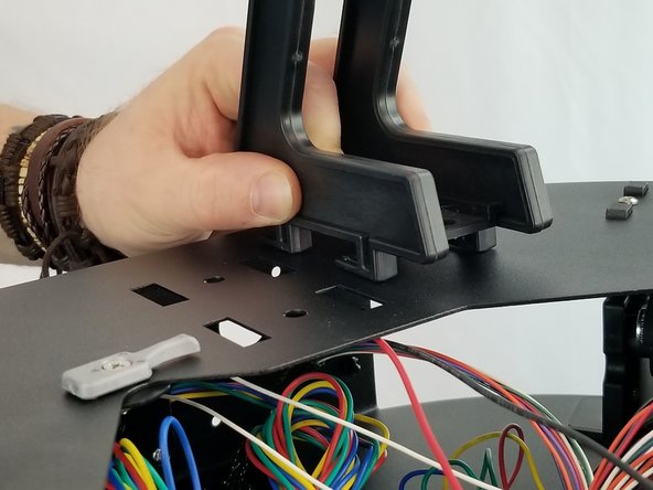 Holding the spool holder side plates together keeping the clamp in place, insert the spool holder side plates into the slotted holes on the top plate of the machine on the side with the extruder.