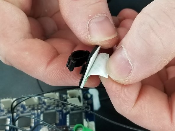 Using one of the adhesive wire clamps, clamp over the ribbon cable for the LCD and remove the adhesive paper.