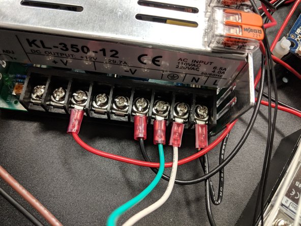 The ground (green) and neutral (white) wires go to their respective locations on the power supply. Unscrew the clamps and reinstall with the ring terminals in place as shown.