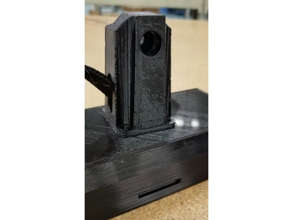 Position the arm on the enclosure as shown, ensuring the flat side with the bolt hole is aligned with the bottom of the screen (indicated by the SD card slot)