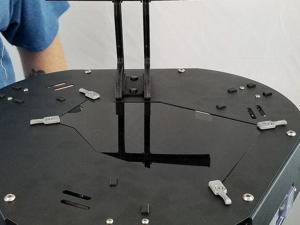 With the 4 built plate clamps rotated away from the large hole in the top plate, place the acrylic hatch in the opening on the top plate.  It will rest on the 4 large washers installed with the build plate clamps as shown in Pic 2.
