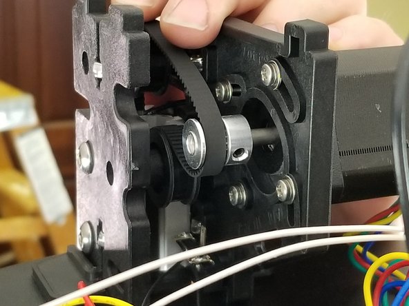 Have the belt follow the inside channel of the extrusion to bring it into the machine below the upper frame.