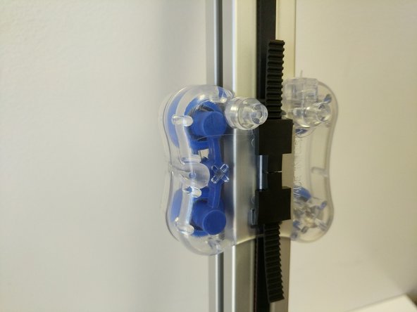 Hold the carriage stationary and pull down on the belt with a decent amount of force, while doing so insert the belt clips legs into the two lower rectangular cutouts. (an extra set of hands for this step may be helpful).