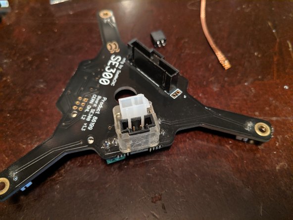 Insert the new power plug into the other side of the retaining ring of the Retro Fit Kit, and insert the legs of the plug through the now-cleaned soldering holes on the board.