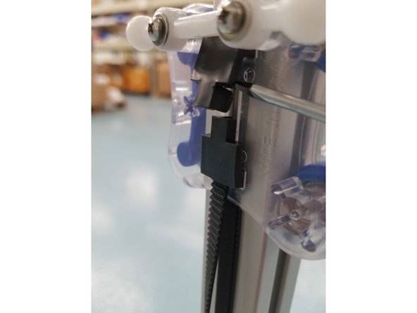 The Next step is removing the top belt clamps from the carriages. To do this take a flat head screw driver and wedge it under the Belt Tension Clamp. Once you have the flat under the clamp you want to give it a counter clockwise quarter turn until the clamp pops free of the carriage.