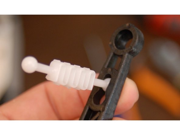 Insert the end of the tension spring into the keyhole notch in the arm as shown.