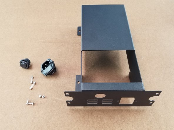 This step we will be assembling the power supply cage.  You will use the sheet metal power supply mount, rocker switch, 2x fuses, 2x M3 nylon insert lock nut, 2x m3 x 10mm long phillips screws, and plug receiver with fuse holder
