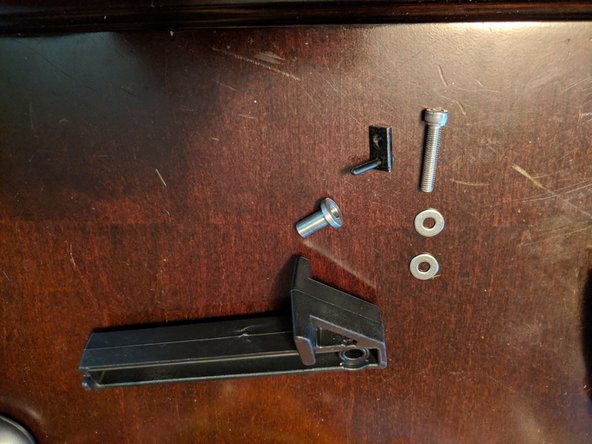 For this step we will need the Spool hanger (large injection molded plastic piece), Stainless steel insert, Threaded screw and 2 washers.