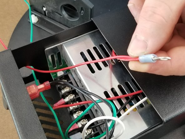 Continuing to work with the red 2-wire harness from the previous step, route the 1350mm red wire out of the power supply enclosure using the same hole as the 1350mm green wire.