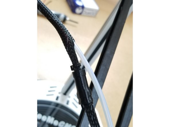 Exit the PTFE tube just before the y-splitter 3D printed part on the whip.