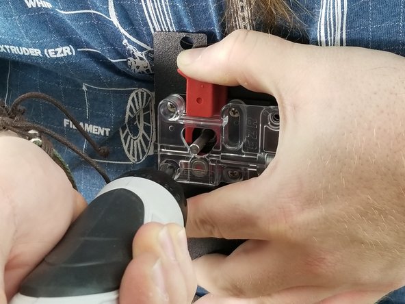 While applying pressure to the red lever, fully tighten the 4 screws to secure the ezr struder to the motor. This will make sure the plastic parts are aligned properly.