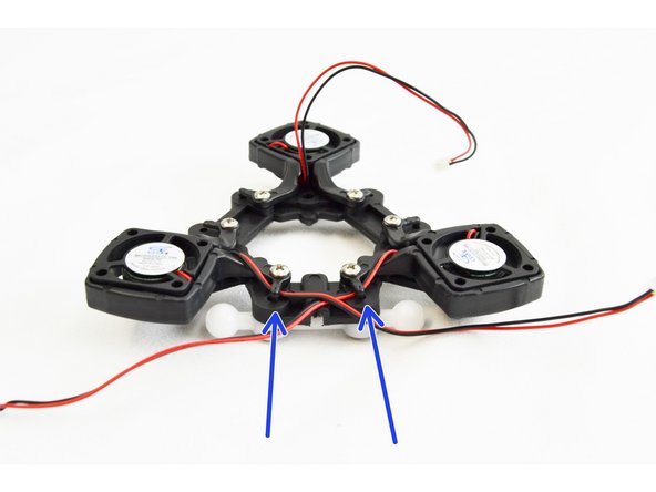 Begin with the (2) layer fans that are closest to the channel in the ball joint platform (indicated by the blue circle).  You will want to GENTLY flex up the wire management tab with a flat tool. You will route the leads of the (2) fans closest to the channel towards that channel.