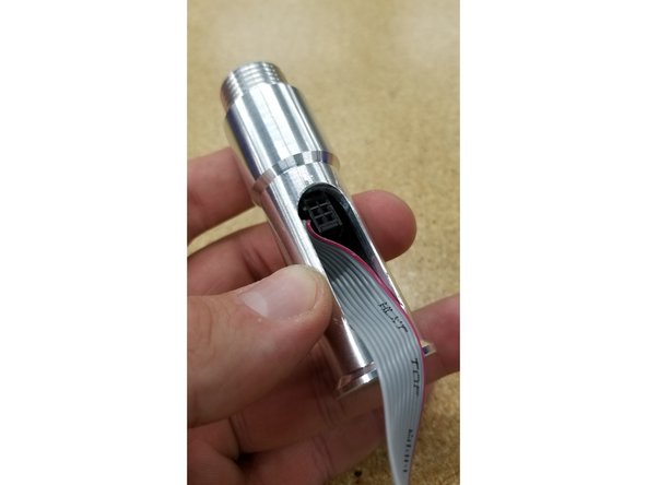 CAREFULLY wedge the ribbon cable through the screen mounting post as shown. The black connector will only fit through the tube sideways!