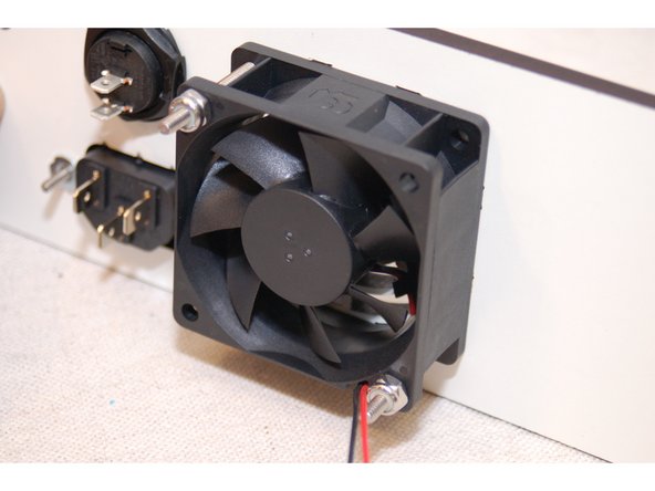 The power supply cooling fan has both rotation and airflow direction marks on the side of the fan. Make sure that the airflow direction arrow points towards the panel.