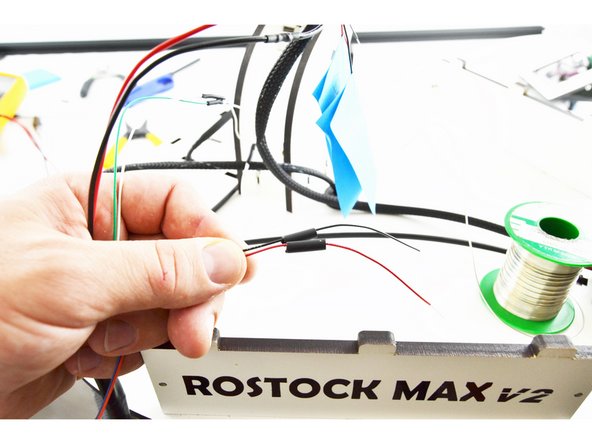 Slide a piece of 15mm long heat-shrink tubing over one of the red wires and one of the black wires.