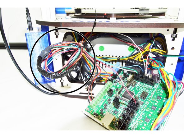 Gently pull any slack wire/whip from the front of the printer. The side panel with the extruder should still be removed, do not pull so much wire/whip  that the cover is moved (we want to be left with enough slack that the cover can be removed in the future is maintenance is required.