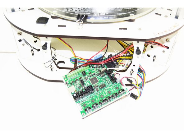 The RAMBo board is mounted to a backer board. You will grasp that backer board on the bottom left and right pull out. The bottom of the RAMBo (and backer) should pull freely and tip out. Once the top ears on the backer board have cleared the top plate of the base, the entire board can be removed.