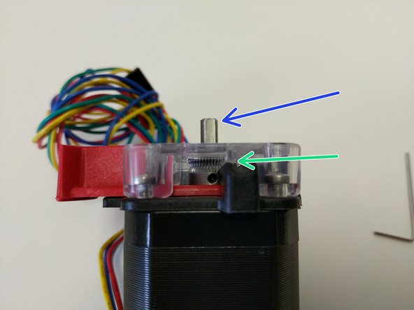 Press the red release lever and slide the hobbed drive roller down into the EZR Struder assembly until the midpoint of the hobbed portion is aligned with the split between the base and cover pieces (indicated by a green arrow)