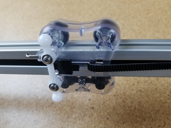 Begin by routing the belt through the top side of the carriage as shown in the first image.