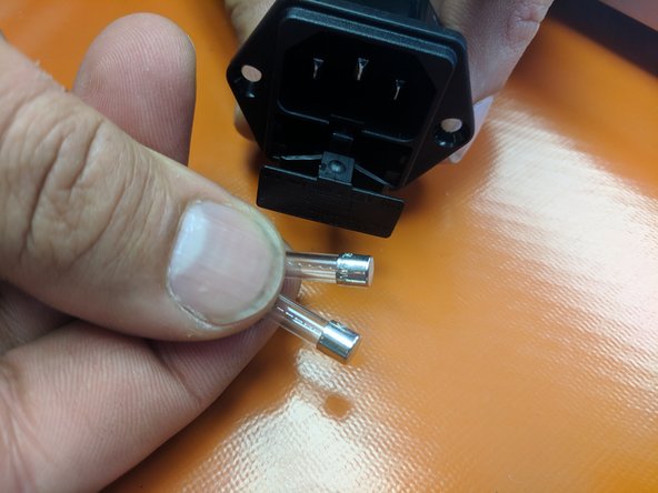 Open the fuse drawer on the IEC connector. Insert the two fuses that were provided into the location. as seen in the image. Close the drawer.