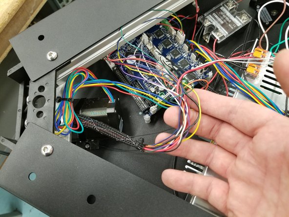Coming from the X tower, a short section of mesh loom houses the hotend whip wires and the extruder wires. Disconnect all connectors on wires exiting this mesh loom.
