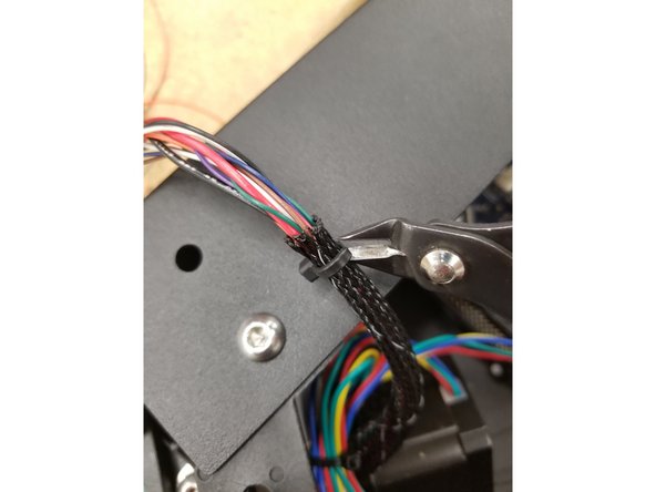 Snip the zip tie on the short section of mesh loom exiting the X tower and remove the mesh loom. This mesh loom is only installed at the factory to prevent wire pinching during the initial machine assembly. It won't need to be re-installed after these steps if you don't wish to.