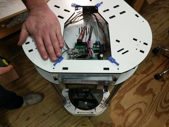 Align the top assembly top plate with the top of the printer. Work your way around the periphery of the top plate while pressing it down onto each set of injection molded tabs. This is a process of finesse, not brute strength.   When complete, the top plate should be resting flush against the injection molded parts in the area of each axis.