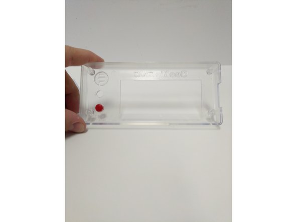 Insert the red button in the enclosure front (from the inside). The flange on the button will prevent it from falling all the way through.