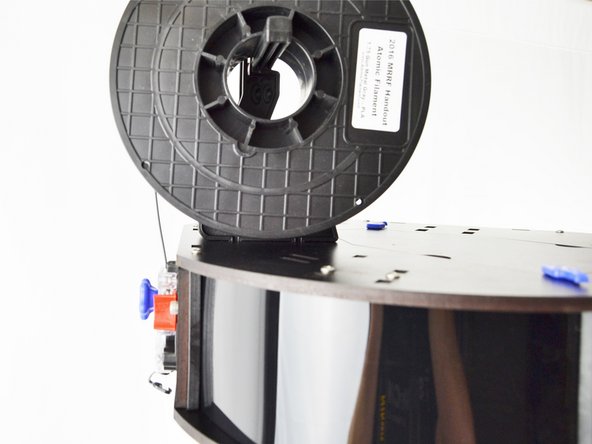 The spool of filament should be installed on the printer so the filament is coming off of the top side and down to the extruder as shown.