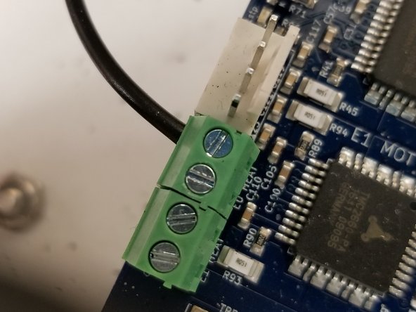 The black 20awg wire from the hotend whip can now be attached to the terminal block as indicated in the photo. You may need to rotate the screw counter clockwise before inserting the wire to open the terminal, as it may be closed from the factory.